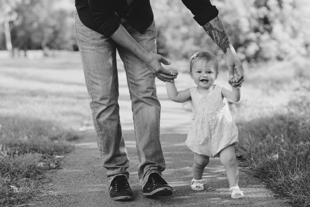 little girl walking holding her dad's hands