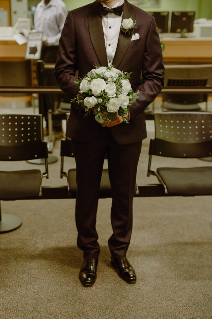 groom holding the wedding bouquet as they wait for the ceremony to start