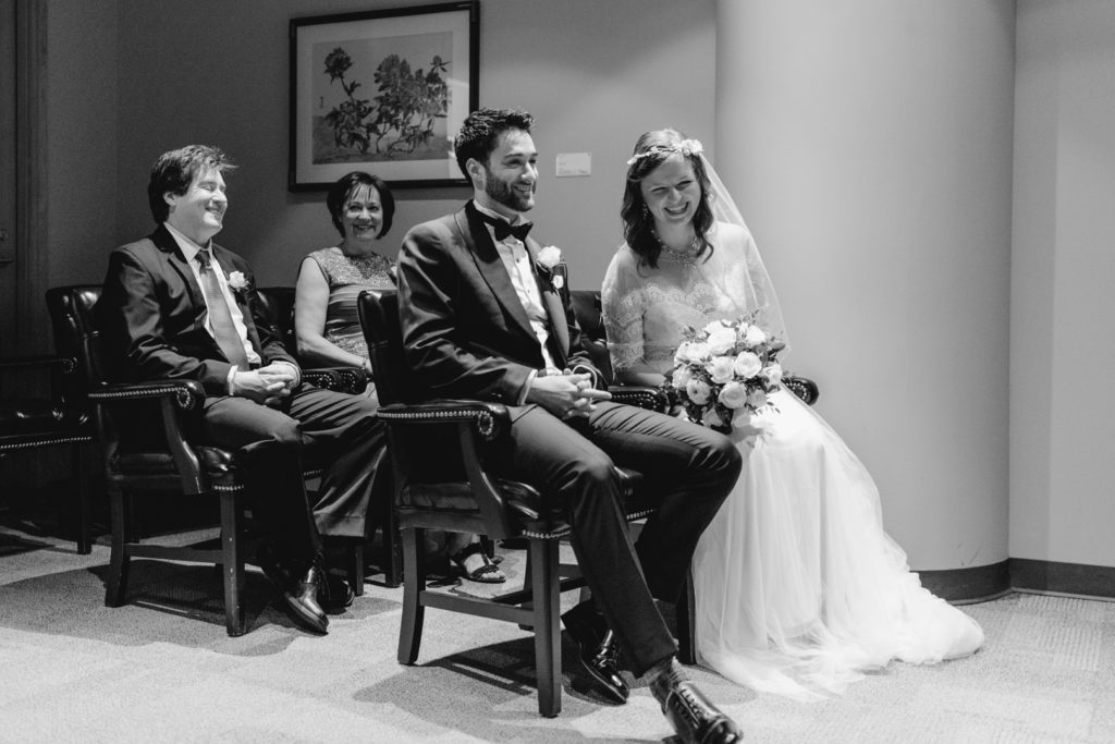 bride and groom and their parents laughing before the wedding ceremony