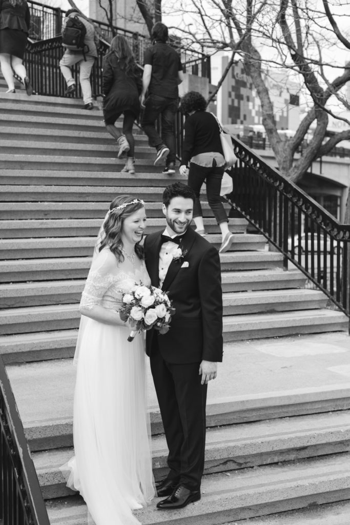 bride and groom laughing on the staircase as pedestrians walk up the stairs