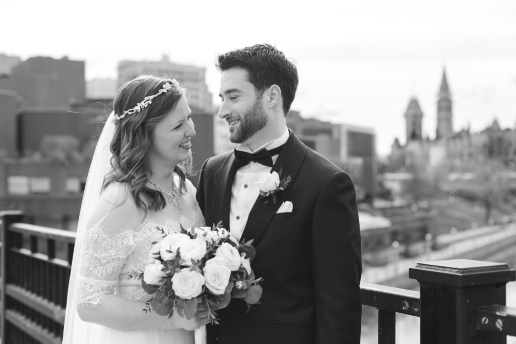 bride and groom smiling at each other with Parliament Hill and the canal in the background