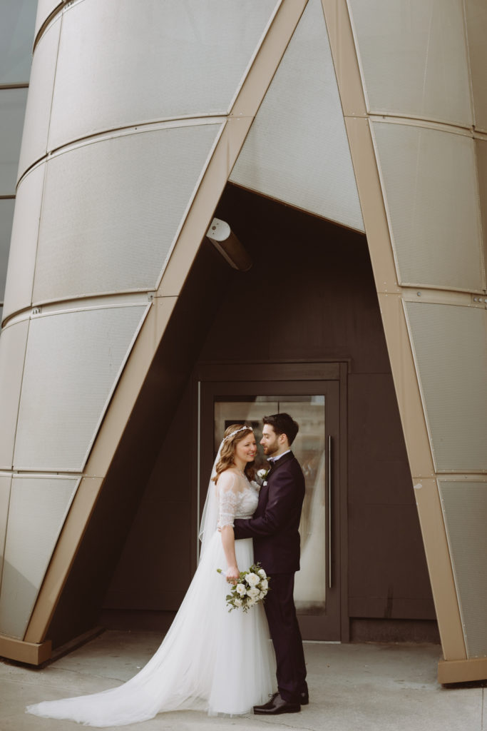 bride and groom standing underneath interesting architecture