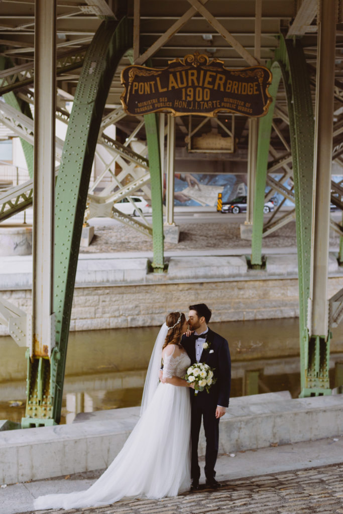 bride and groom kissing under the Laurier Bridge in Ottawa