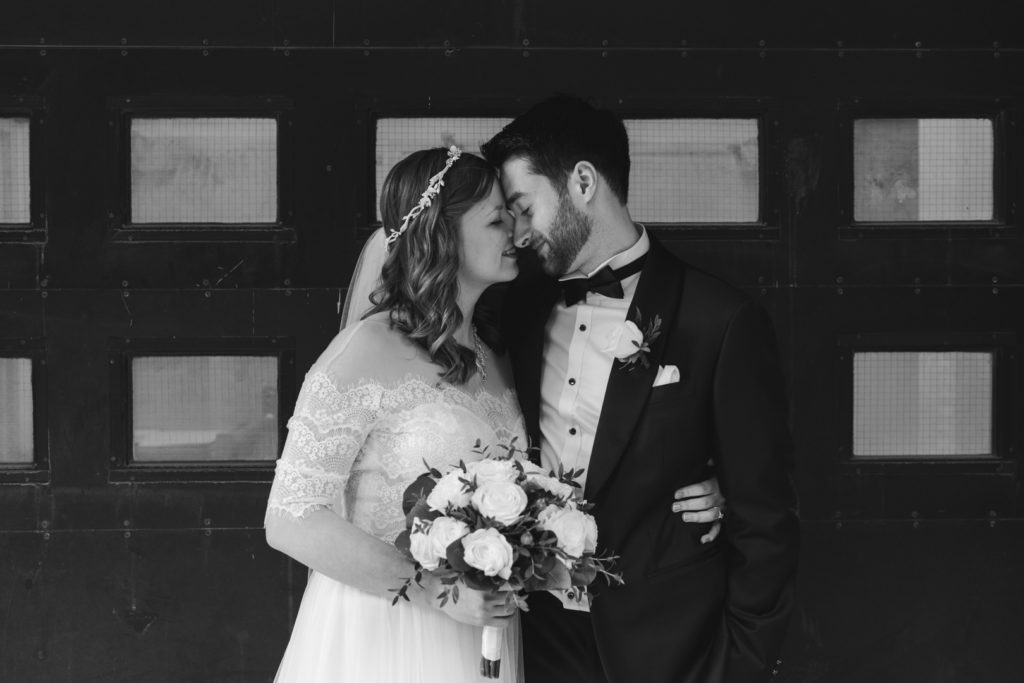 bride and groom cuddling in front of old loading dock door