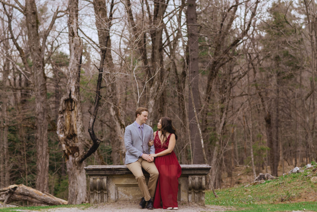 engaged couple sitting on stone ruins in the forest