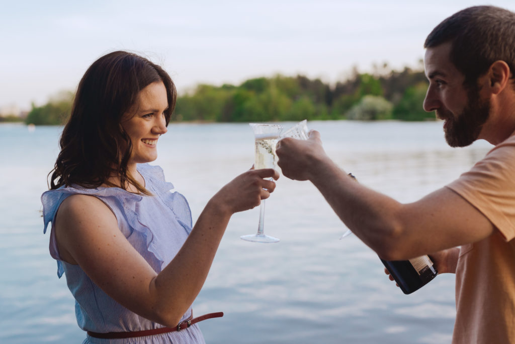 engaged couple toasting with champagne by the water