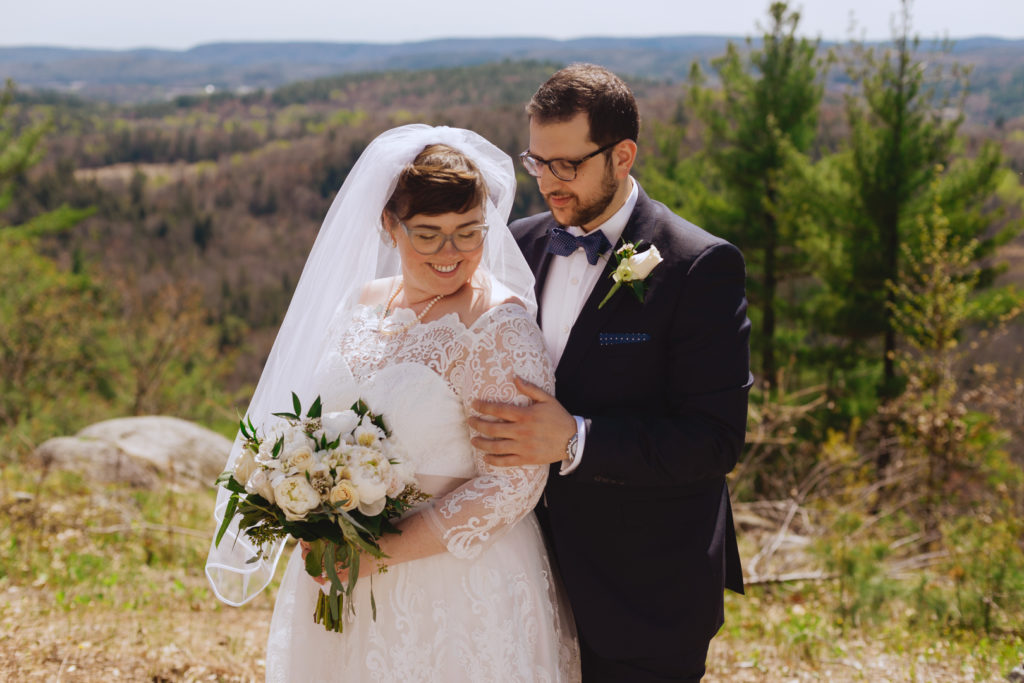 bride and groom on top of a cliff overlooking the Gatineau hills