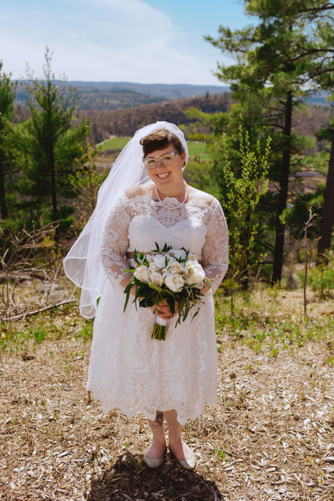 bride smiling at the camera on top of a cliff overlooking the Gatineau hills