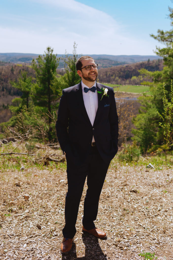 groom standing on top of cliff overlooking the Gatineau hills