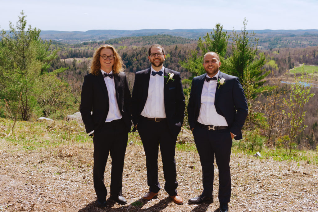 groom and groomsmen standing on top of cliff overlooking the Gatineau hills