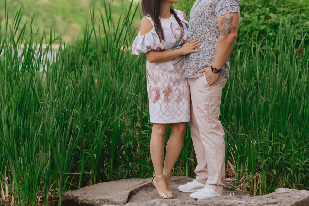 engaged couple standing on a rock by the tall grass