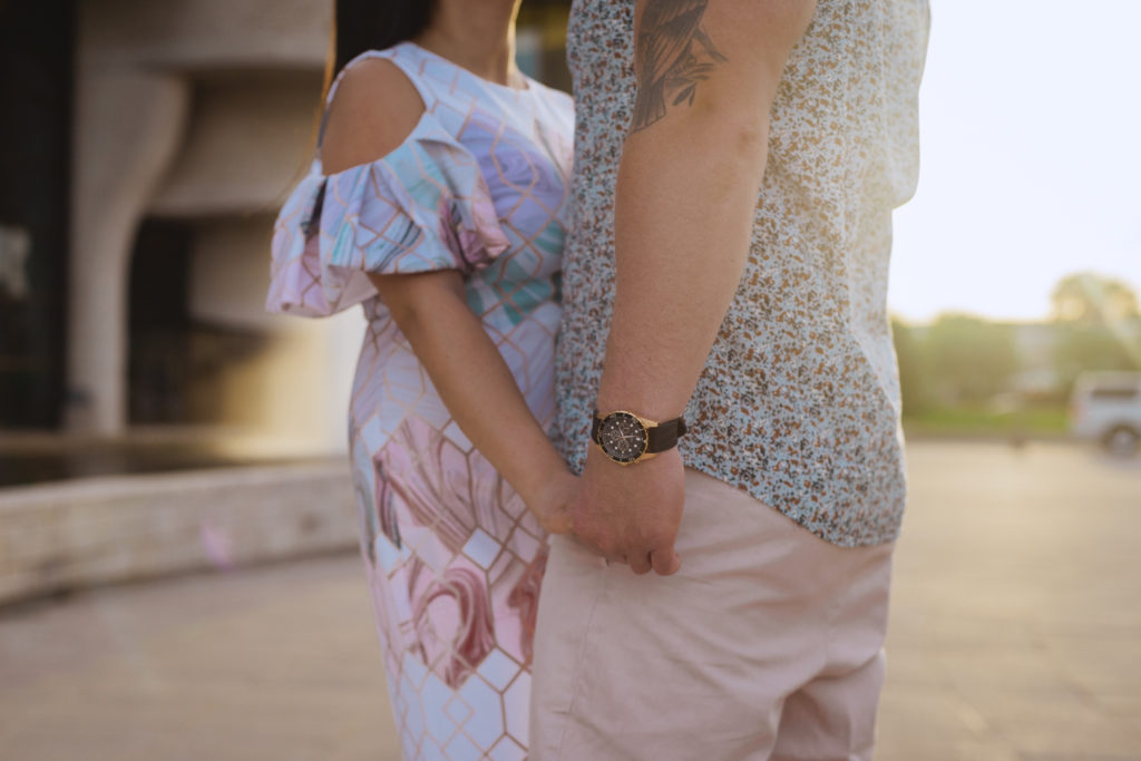 engaged couple holding hands at sunset