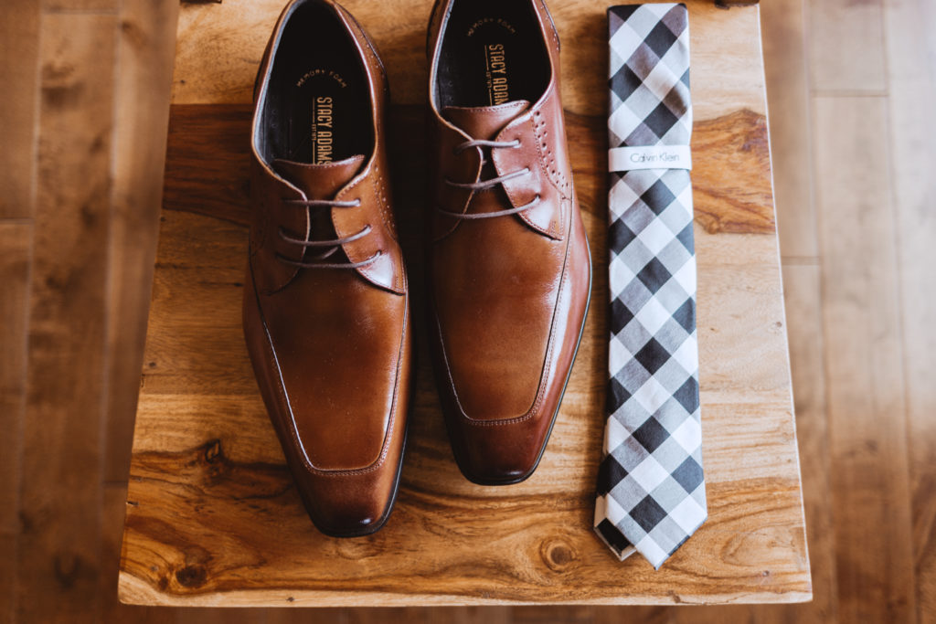 groom's shoes and tie resting on wooden chair