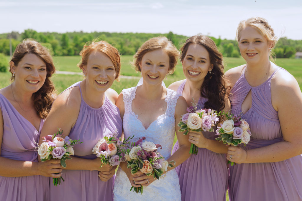 bridesmaids giggling together outside in a field
