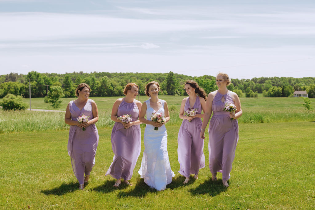 bridesmaids walking in a field with the bride