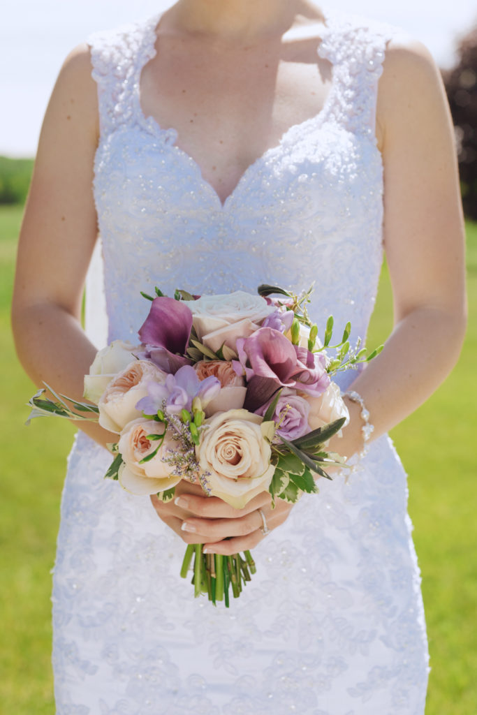 bride holding her bouquet of purple and white flowers