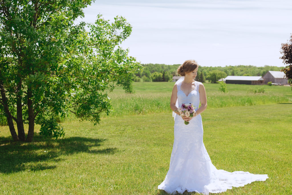 bride standing in a sunny field