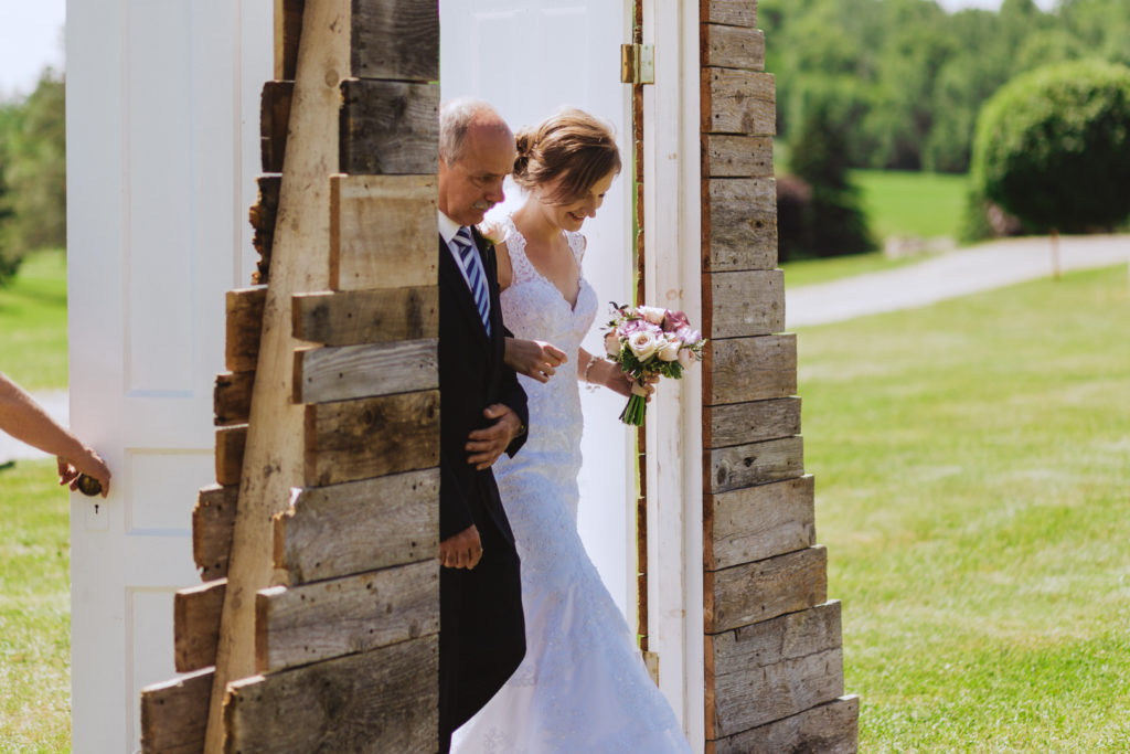 bride and her father walking through wooden doors down the aisle
