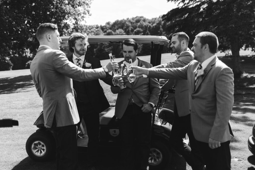 groom and groomsmen hanging out on golf carts drinking beer at the Oaks of Cobden golf club