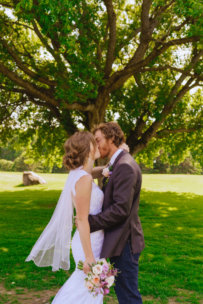 bride and groom kissing underneath maple tree at the Oaks of Cobden golf course
