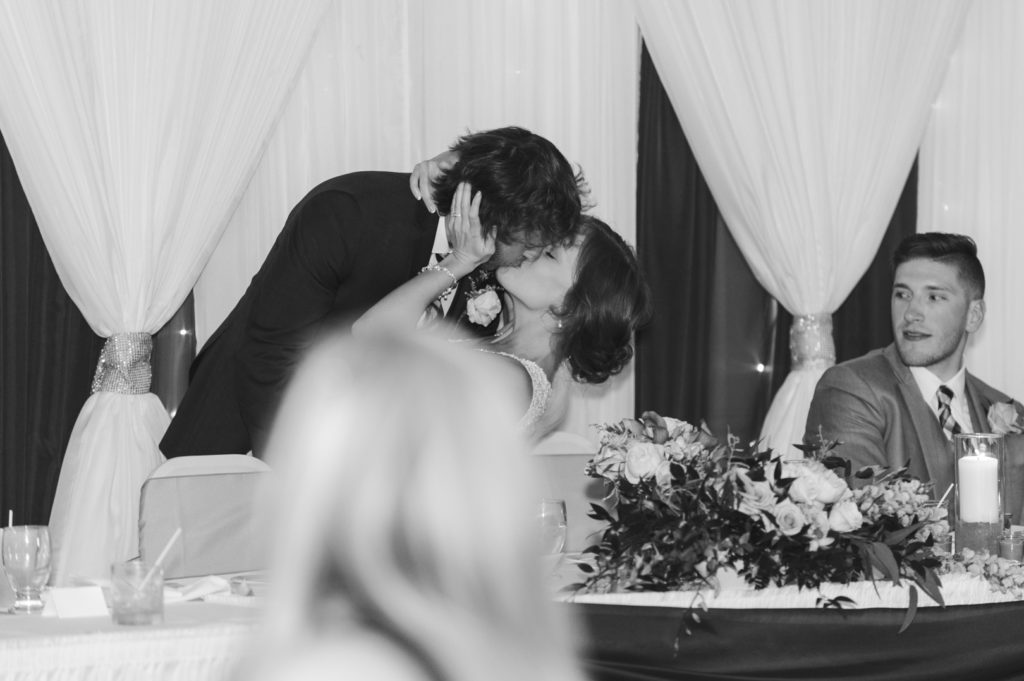 bride and groom kissing at the head table