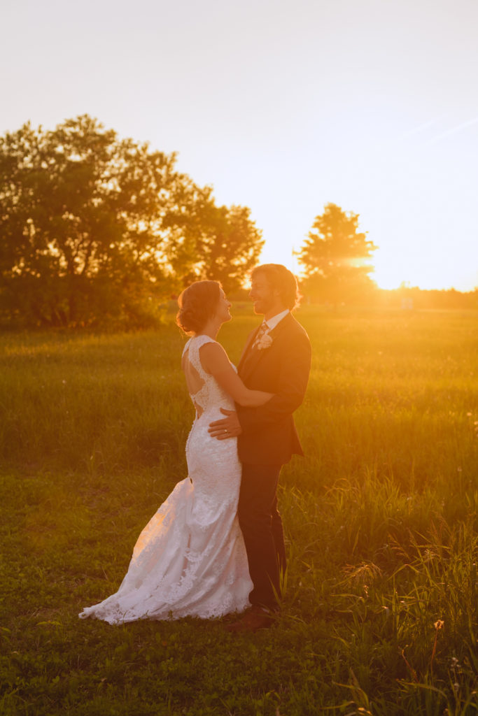 bride and groom at sunset in a field