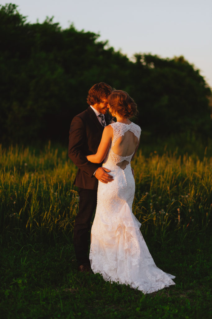 bride and groom at sunset in a field