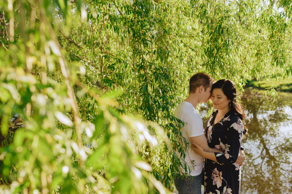 engaged couple cuddling among the willow trees