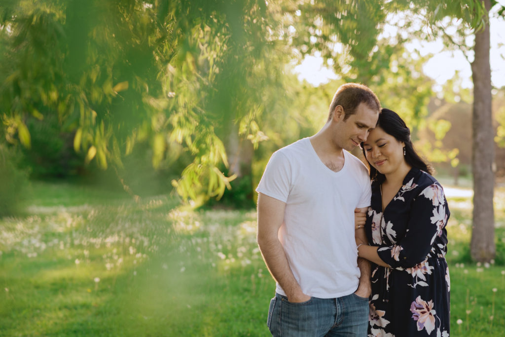engaged couple cuddling among the willow trees