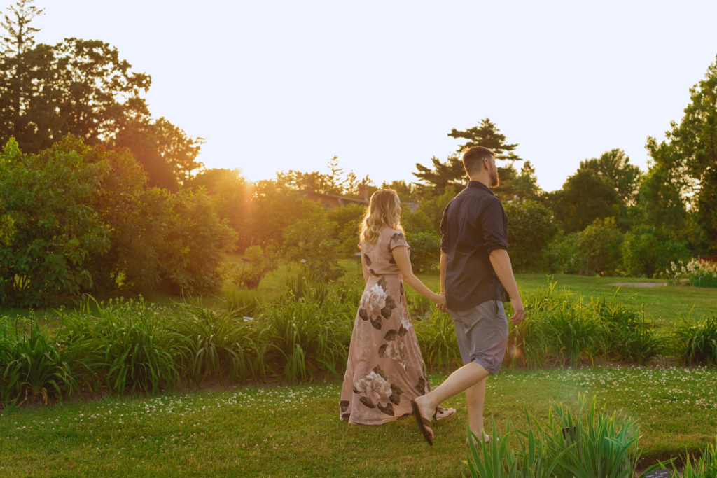 couple walking through the ornamental gardens at sunset holding hands