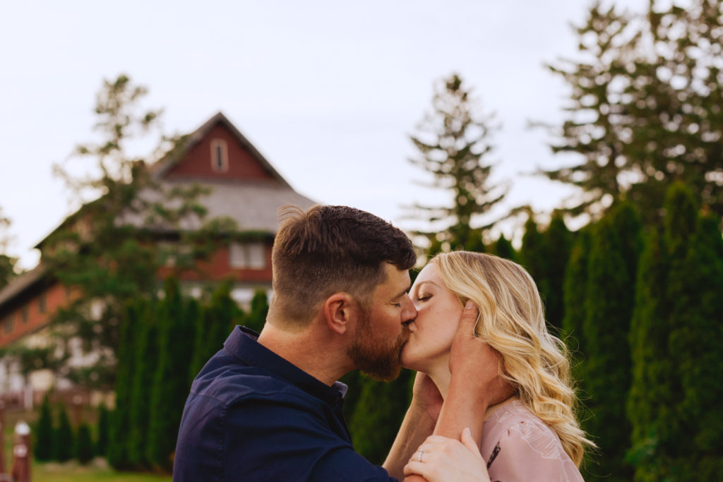 engaged couple kissing with red barn in the background