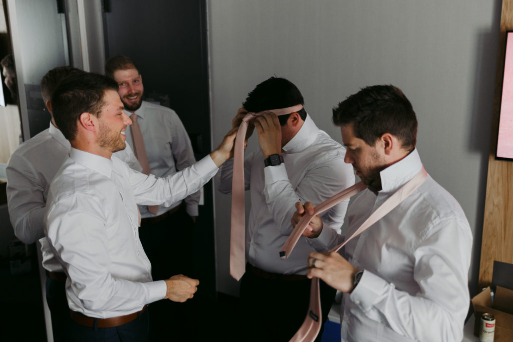 groom and groomsmen putting on their ties