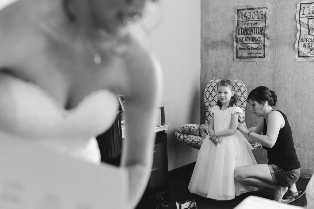 flower girl getting dressed in the corner of a busy room