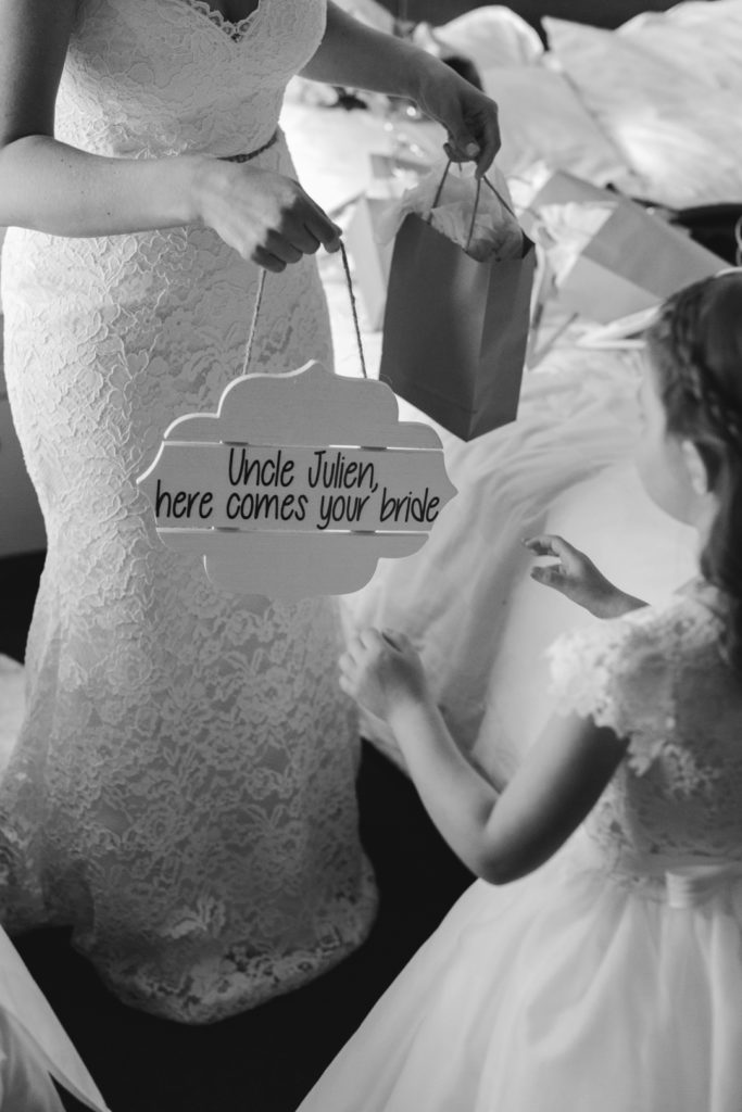 bride giving the flower girl her sign to walk down the aisle with