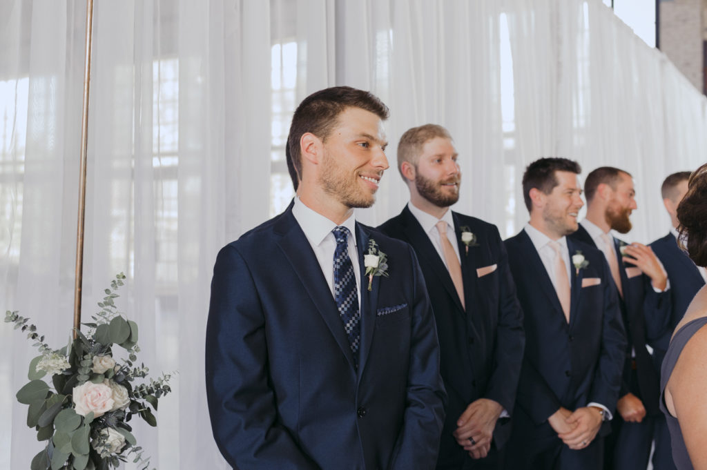 groom smiling as the bride comes down the aisle