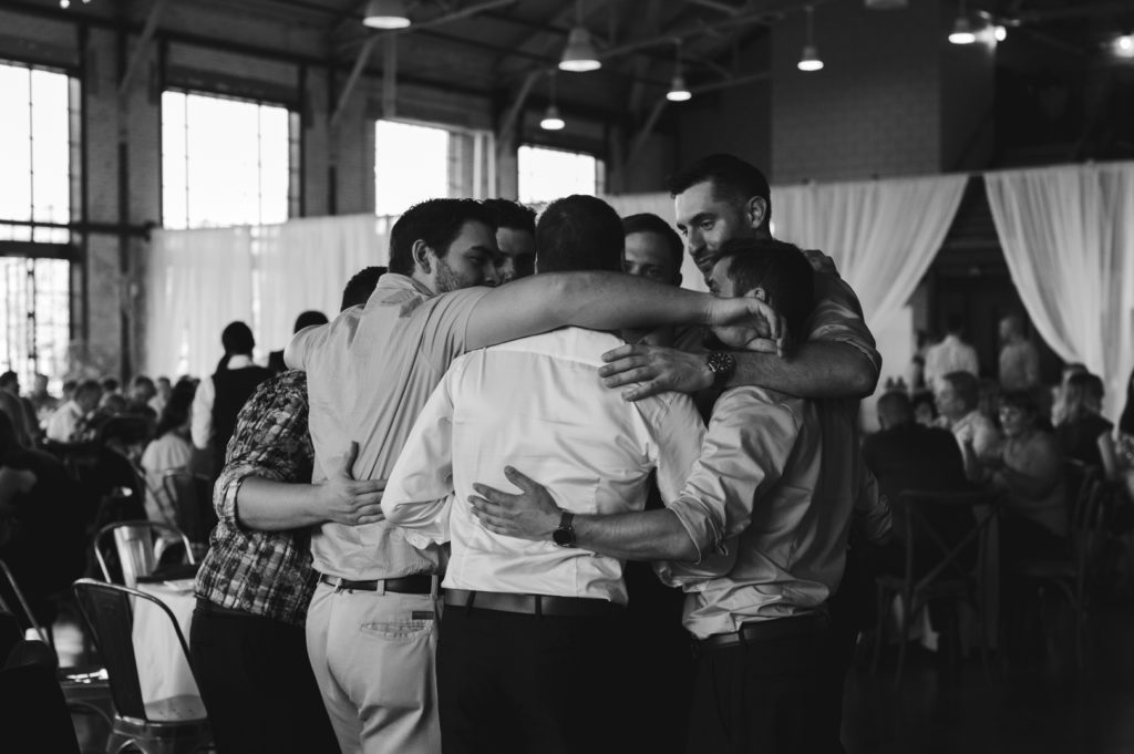 groom and hockey buddies hugging during wedding reception