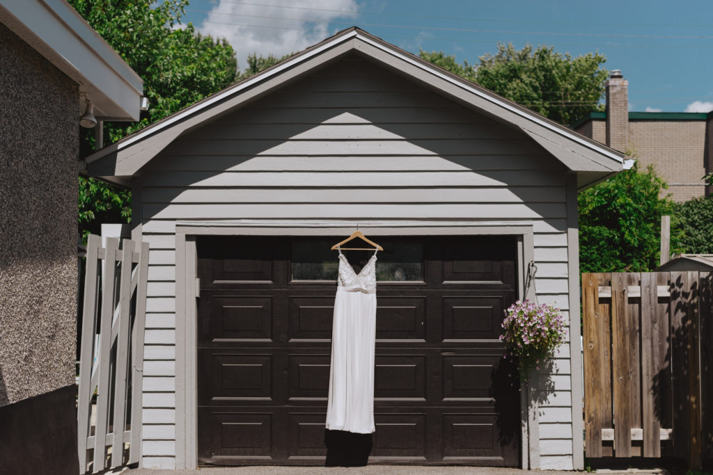 Truvelle dress hanging from a garage door glistening in the sun