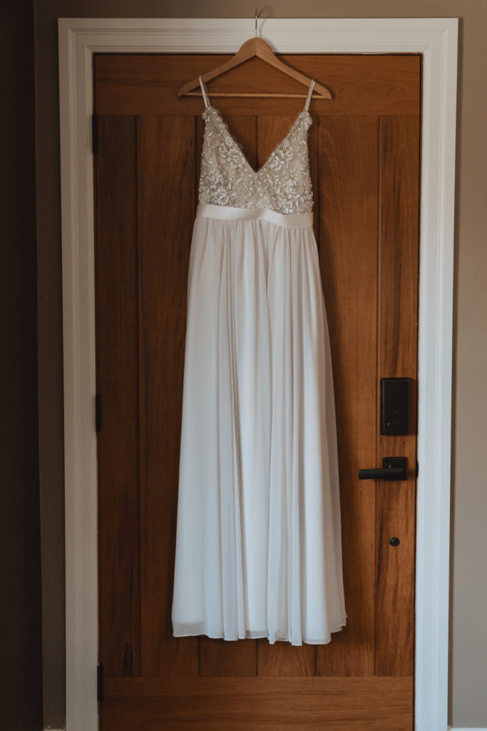 Truvelle wedding dress hanging from wooden door