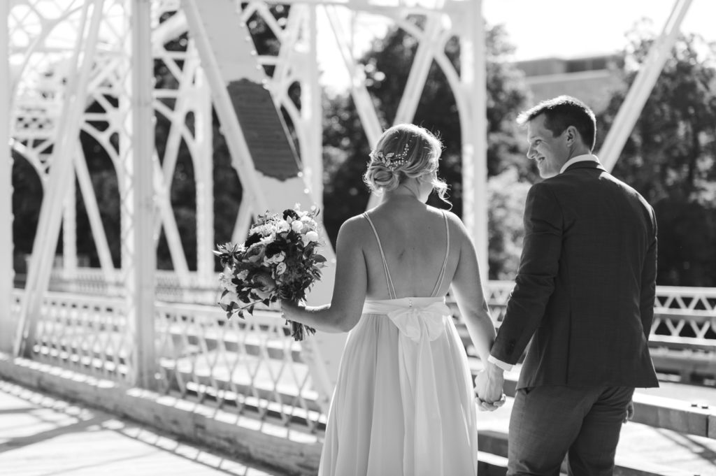 bride and groom holding hands walking down Union Street Bridge in Ottawa