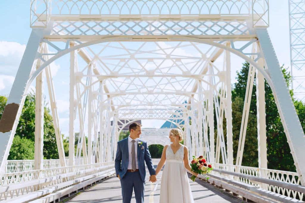 bride and groom holding hands under the Union Street Bridge in Ottawa