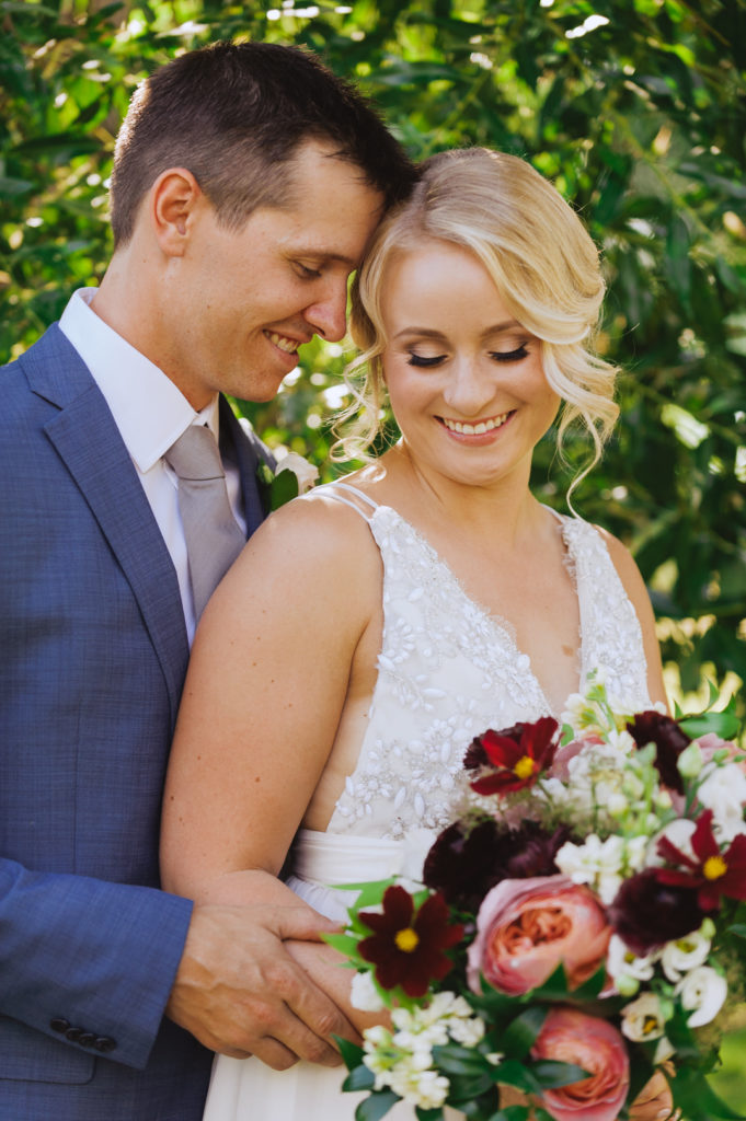 bride and groom cuddling with beautiful wedding bouquet from Pollen Nation