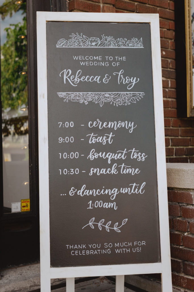 chalkboard sign outside of venue with itinerary for the evening by the Happy Ever Crafter