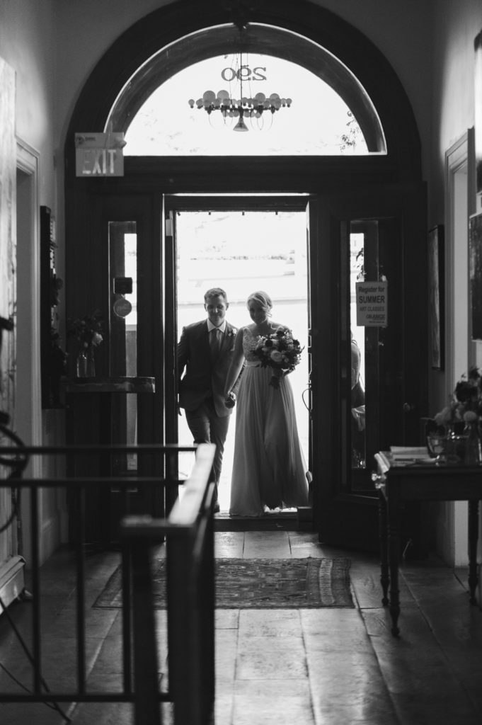 bride and groom walking into the Orange Art Gallery together for their wedding ceremony