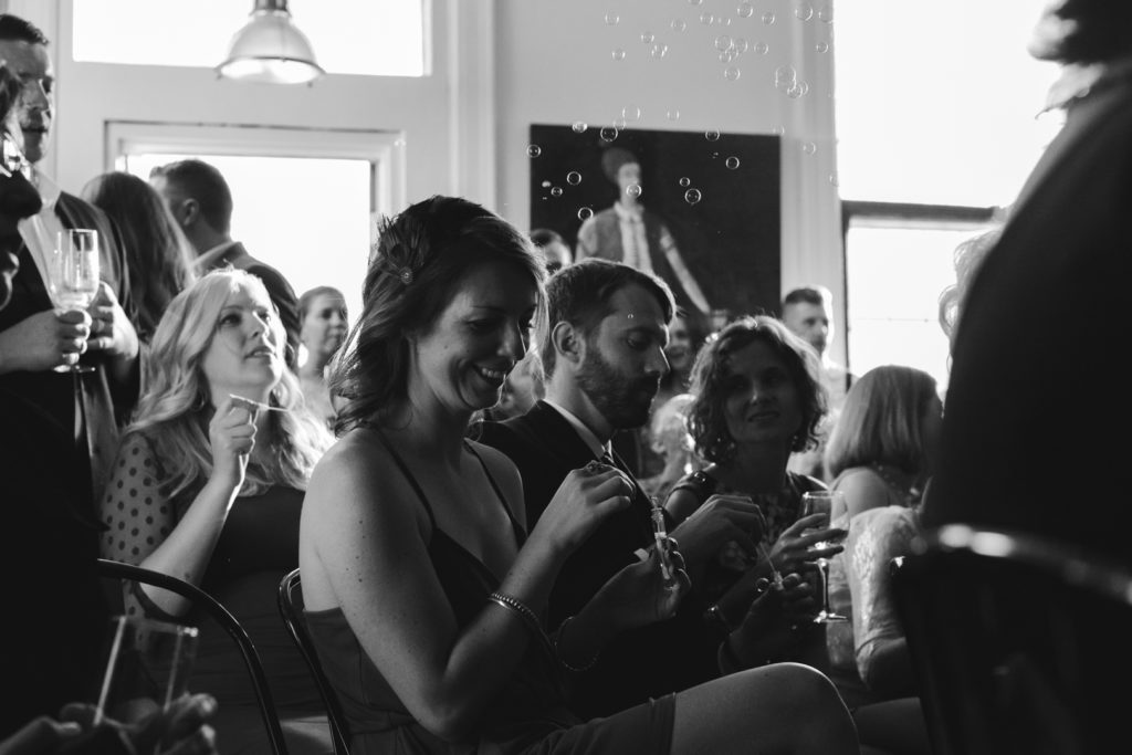 guests blowing bubbles during wedding ceremony
