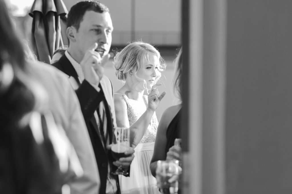 bride and guest talking to friends, both making the same hand gesture
