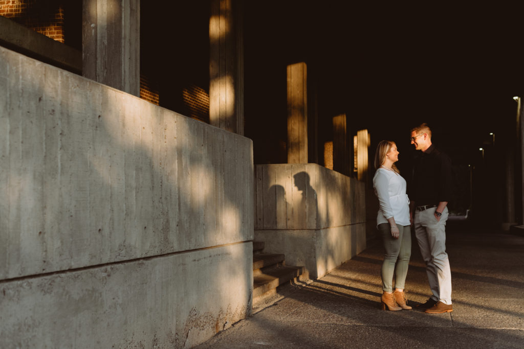 engaged couple standing in a loading dock area at sunset