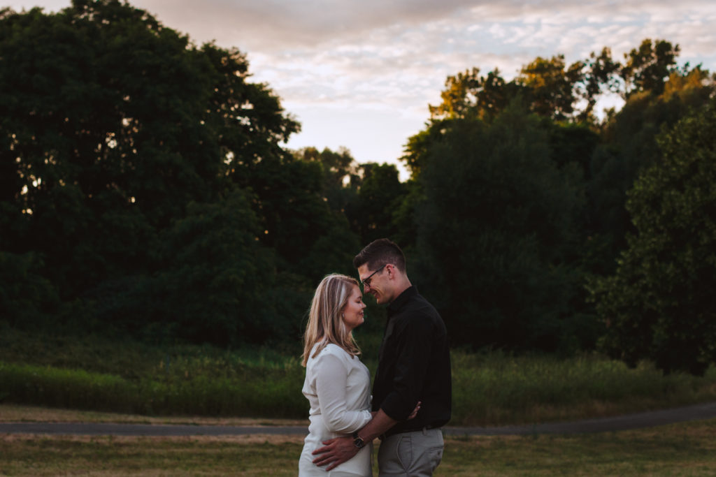 couple cuddling close in a field at sunset