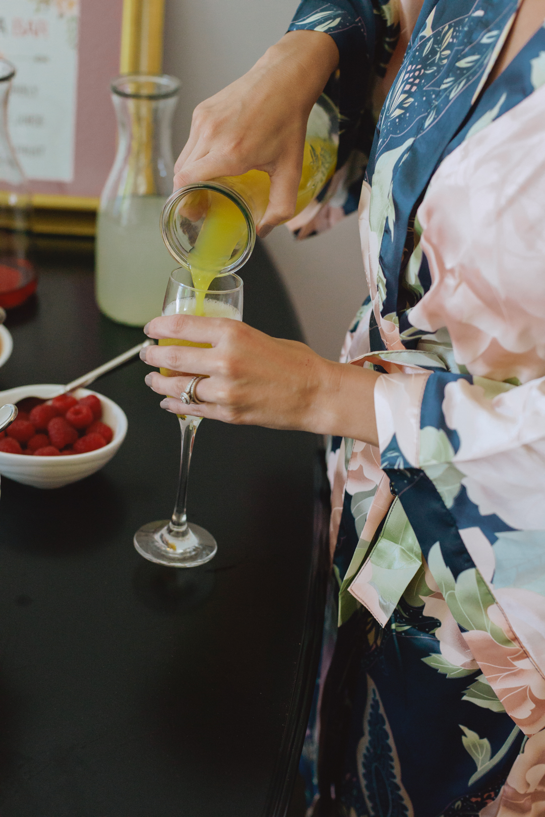 bridesmaid in silk robe pouring herself a mimosa