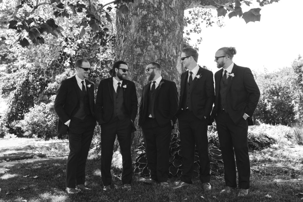 groomsmen wearing sunglasses underneath a tree