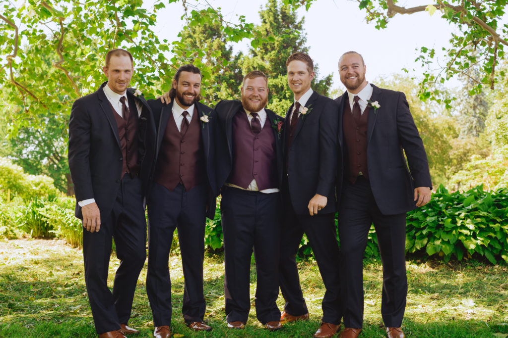 groom and groomsmen smiling underneath a tree in the Ornamental Gardens